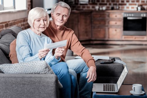 Älteres Ehepaar auf Couch betrachtet Brief