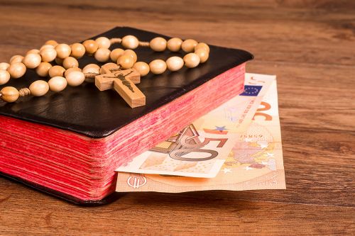 Gebetsbuch mit Geldscheinen und Kruzifix
